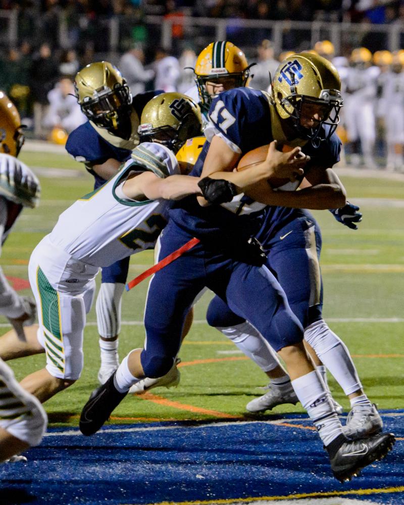 Grosse Pointe South High School running back Max Gavagan, 17, outmuscles a tackle attempt from...