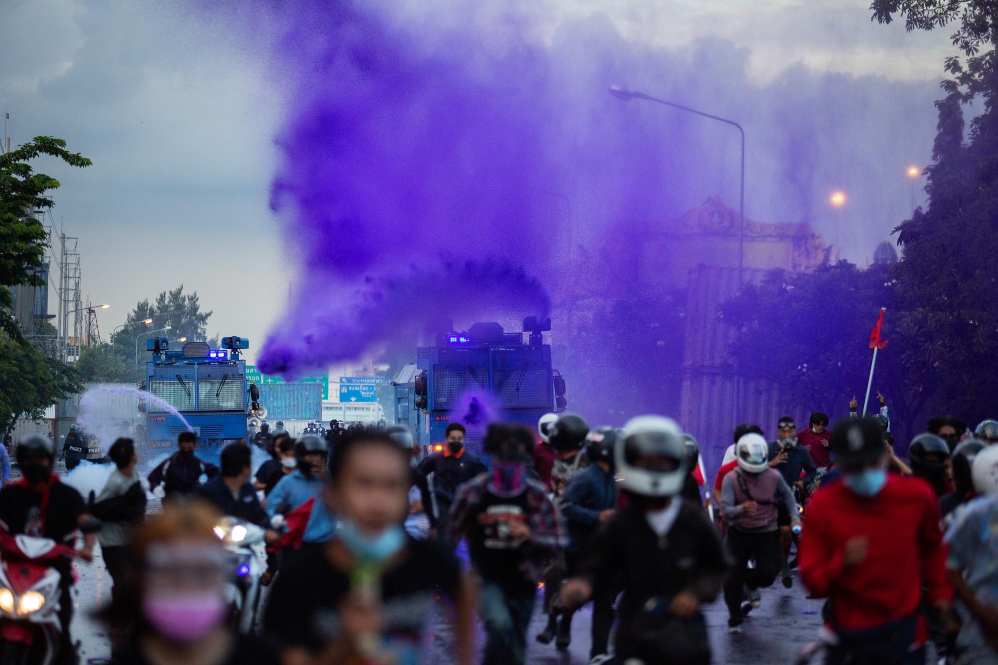 Pro-democracy protestors flee from chemical water cannon&#39;s during clashes with riot police at Din Daeng intersection in Bangkok, Thailand, August 2021. Riot police switched to the strong chemical water seen here, after protestors began to counter tear gas with gas masks and tear gas canister neutralization methods, defense against water cannons is limited to running and hiding.