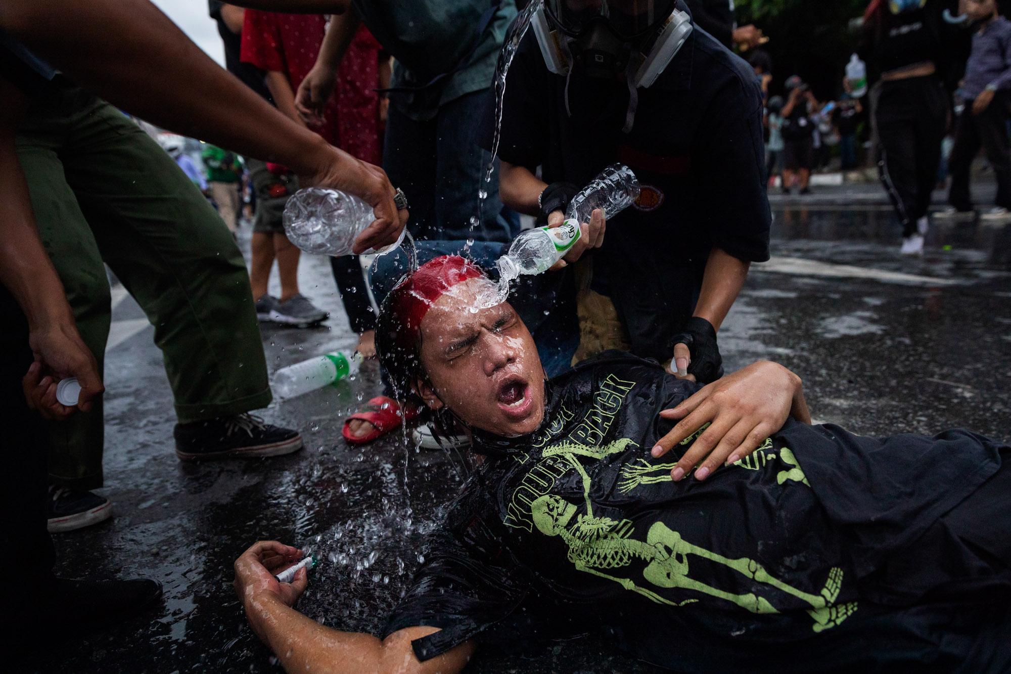 Thailand's Youth Fights Back - A pro-democracy protestor has tear gas washed from his...
