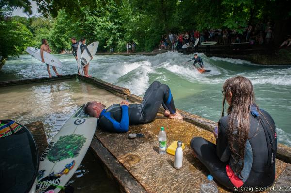 MUNICH, GERMANY - JUNE 15: Surfers relaxing and enjoying the spectacle of &#39;Standing Wave&#39; of the Eisbachwelle in Munich, Bavaria in 2019. The Eisbach (Ice Brook) is a 2 kilometer man made river which is in effect a canal tributary from Bavaria&lsquo;s Isar River. It runs through Munich&lsquo;s Englischer Garten, a public park, and is the hub of the land locked city&rsquo;s surf scene The river, following enhancement from local surfers, produces a standing wave called the Eisbachwelle (Ice Brook Wave). It has been surfed in the city since the early 1970&rsquo;s. Munich now claims to be home to some 2000 full time surfers. (Photo by Craig Stennett/Getty Images)