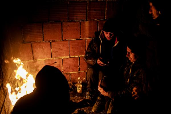 Refugees from Afghanistan and Pakistan, warm themselves by a fire, in an abandoned building in the city of Bihac. getting ready to go to &quot;The Game&quot;, a nickname given by refugees to their relentless attempts, crossing the Bosnian-Croatian border, without being detected and pushed back by Croatian border police.