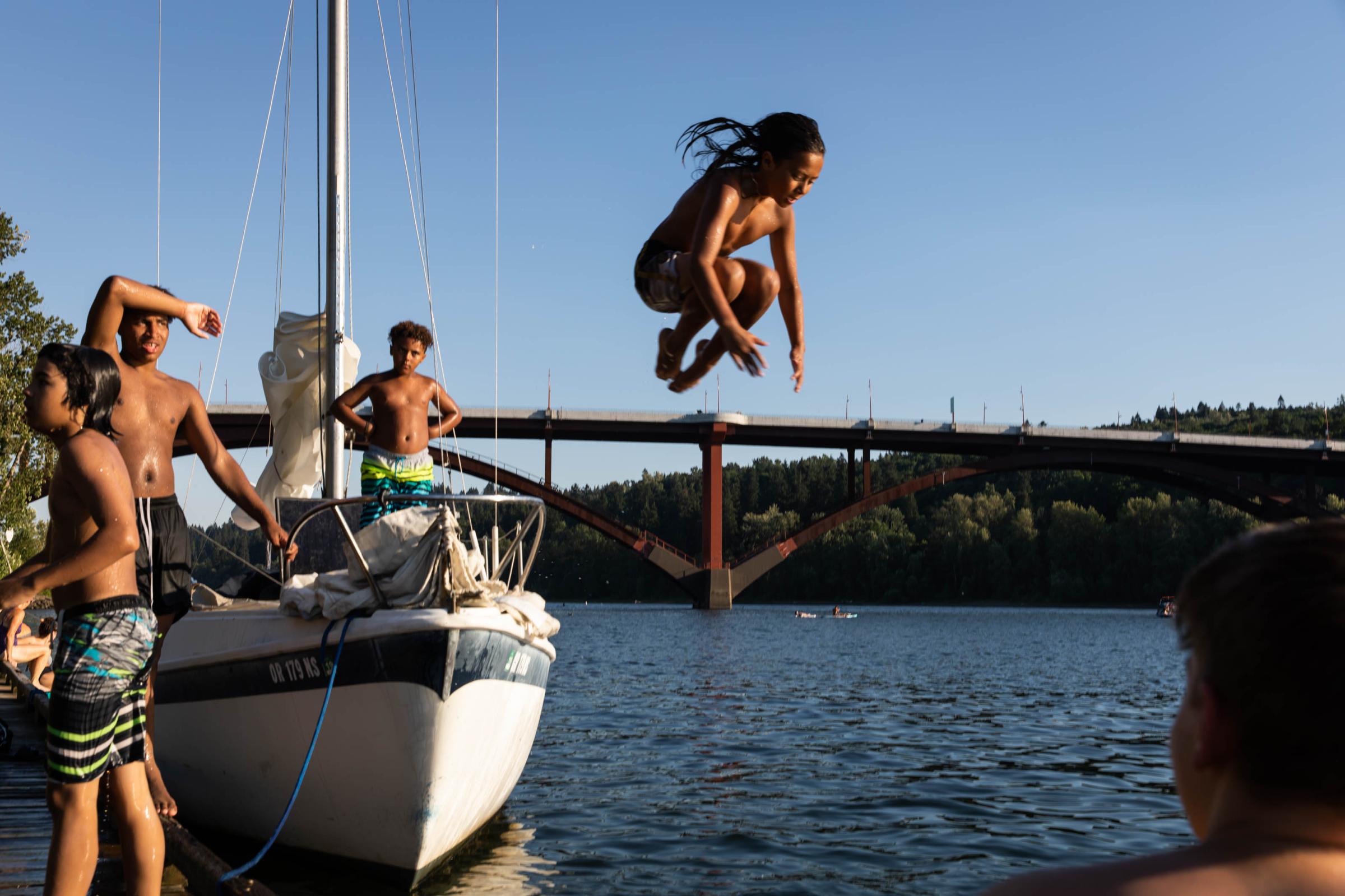 2021 in pictures - Surrounded by friends, a boy jumps into the Willamette River at Sellwood Riverfront Park in...