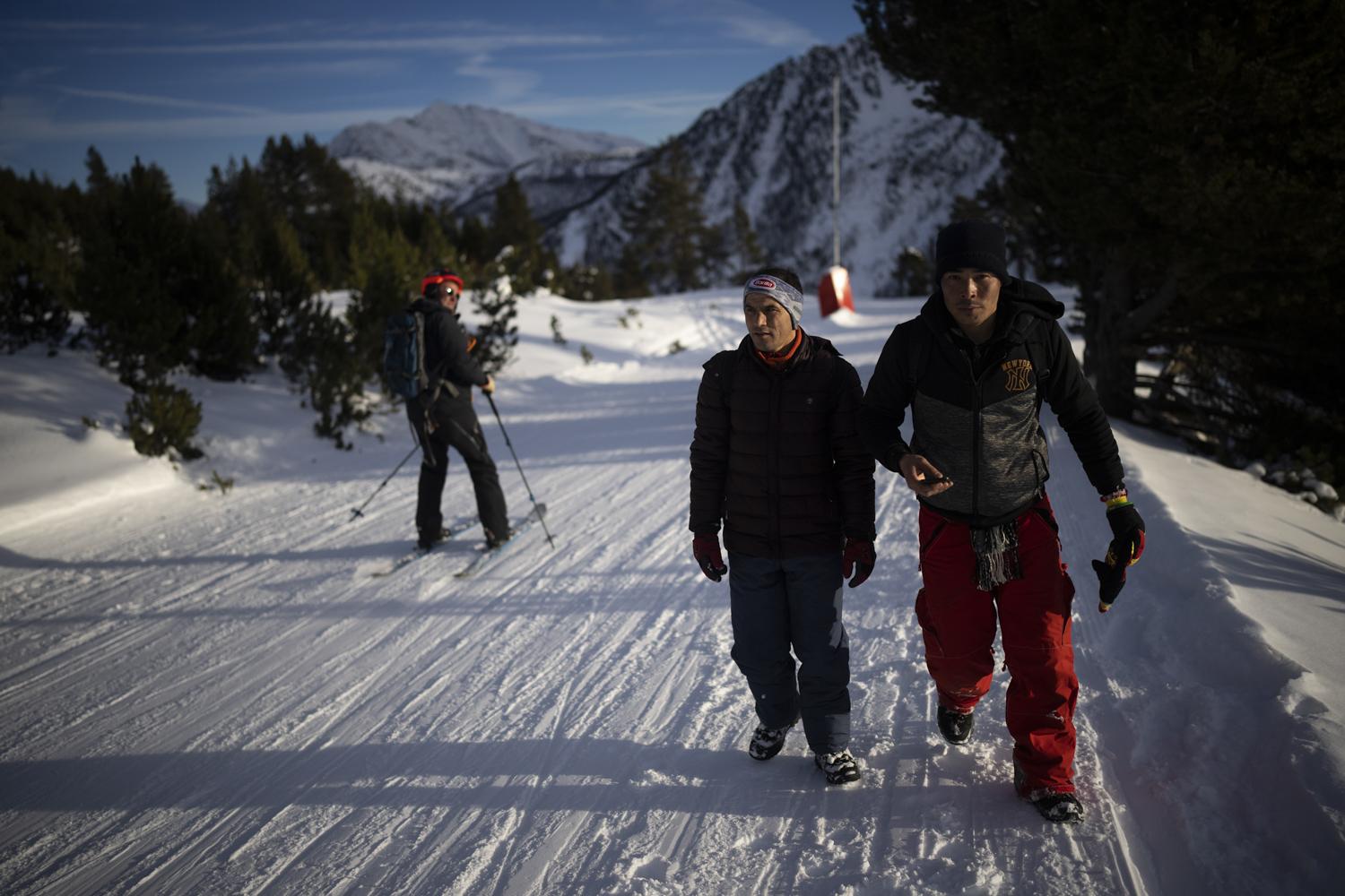 Alps Migrants - A skier passes by Afghan migrants Sayed Hamza, left, and...