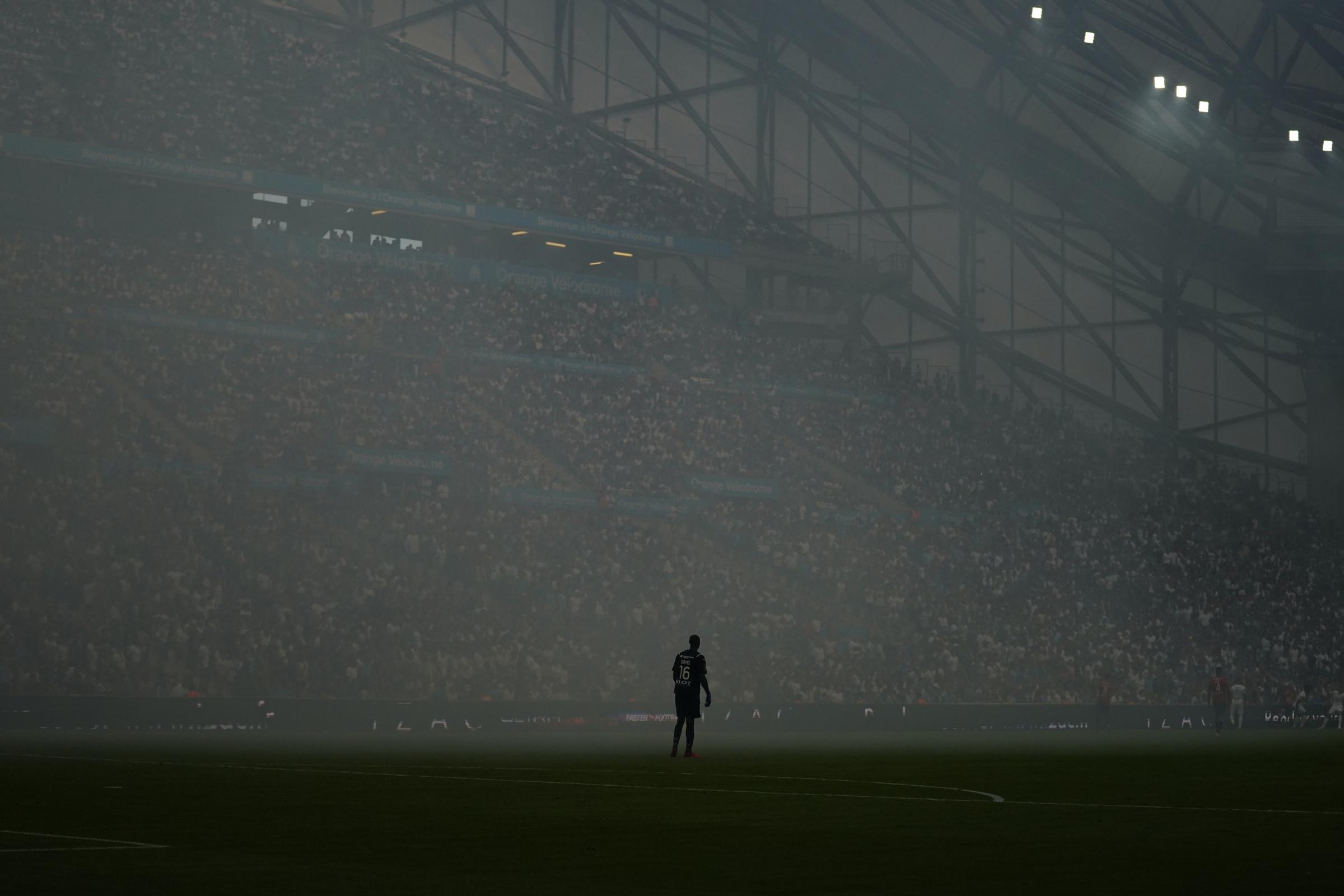 Rennes' goalkeeper Alfred Gomis stands in heavy fog caused by flares after Marseille's...