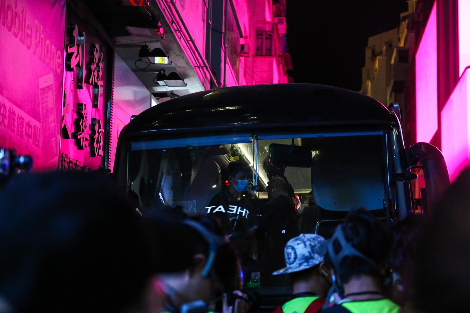 On the first day of the National Security Law in Hong Kong, thousands took to the streets in defiance. Leading up to the nighttime, police can be seen leading arrested protestors onto a bus, who will be transferred to a police station later on. Since the passing of the NSL in July 2020, 93 individuals have been arrested under this piece of legislation, which punishes acts of secession, subversion, foreign interference, and terrorism with up to life imprisonment. In the most dramatic act yet, 53 individuals who had participated in unofficial democratic primaries months earlier were arrested in a single day.