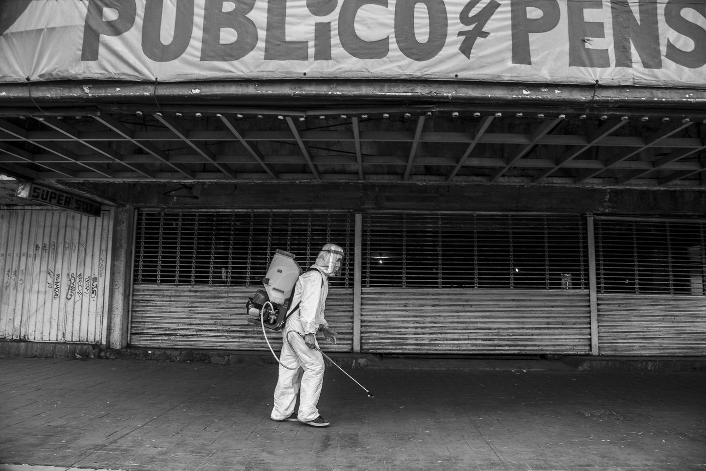 Letters from a distance - A Mexico City government worker walks the streets spraying with a disinfectant liquid what he...