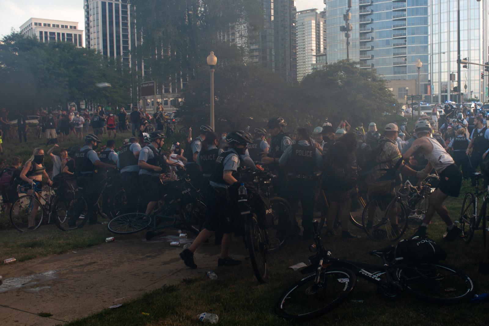 The Storming of the Columbus Statue  - A line of Police push bikes in a retreat against protestors.