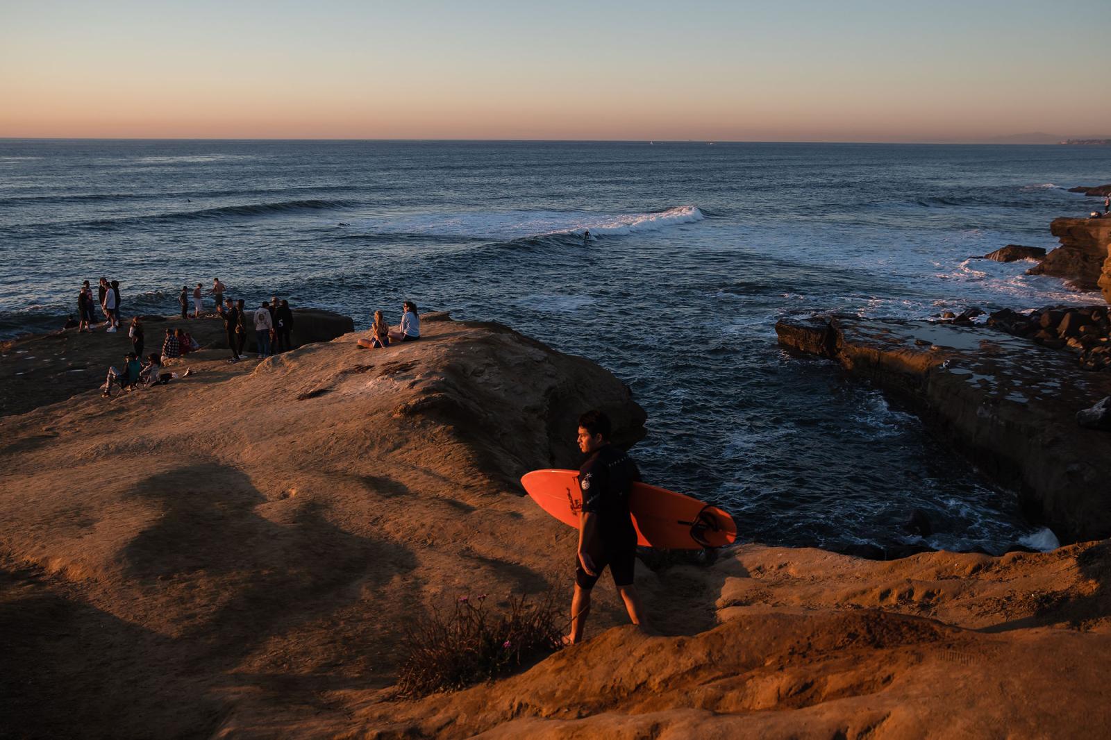 United States - A surfer walks towards the beach at Sunset Cliffs in San...