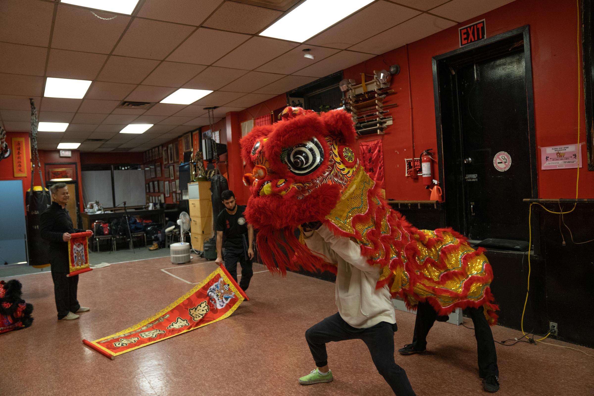 Members of the lion dance team at the Hong Luck Kung Fu Club using a golden and red lion during practice in preparation for the 2022 Lunar New Year...