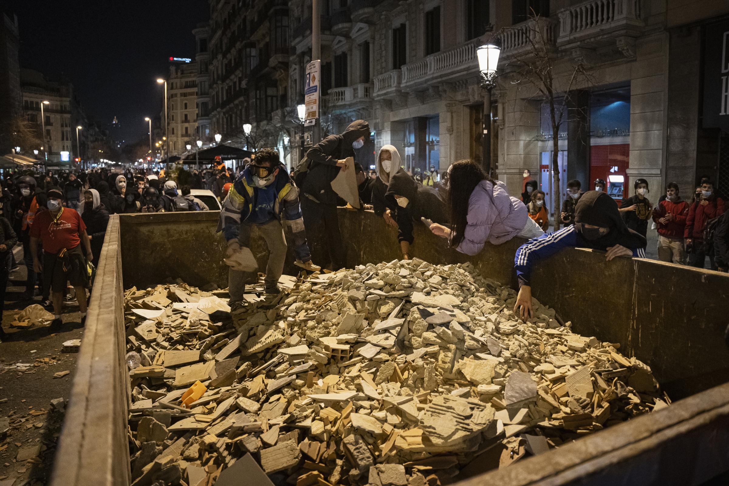 Demonstrators take stones from a construction container on the Rambla de Catalunya to throw them...