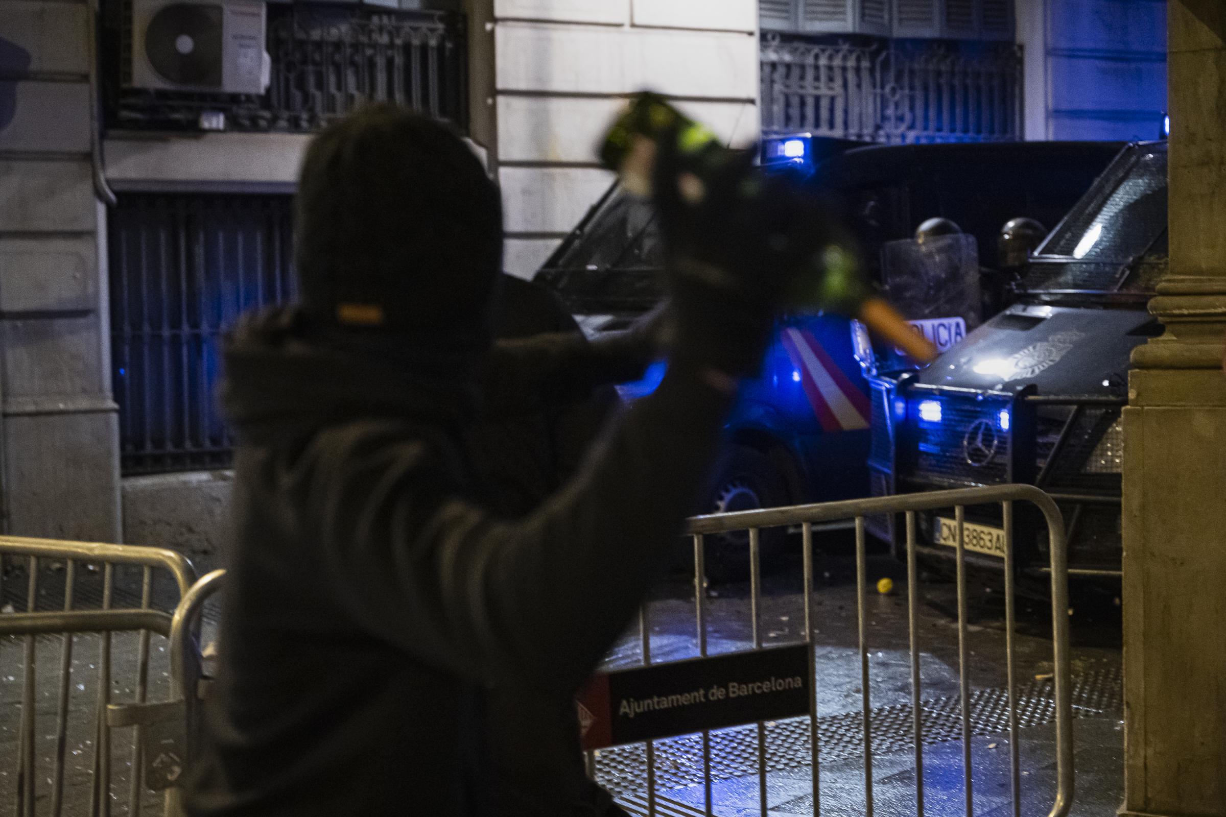 A young man throws a glass bottle at the national police in Via Laietana, Barcelona.