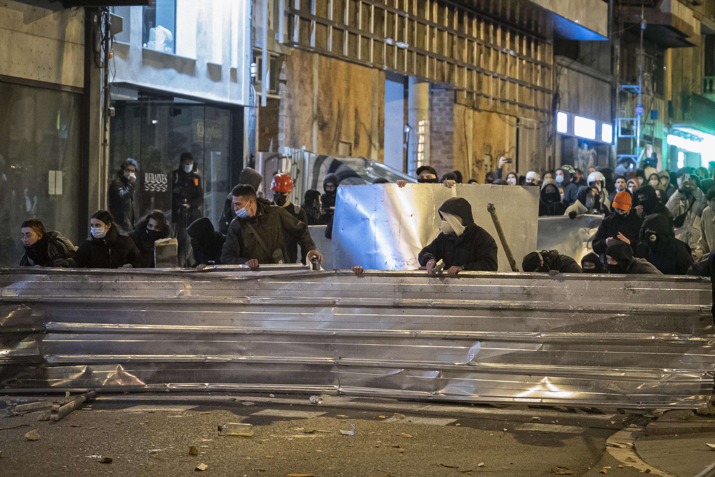 Demonstrators protect themselves, from the projectiles launched by the police, with elements...