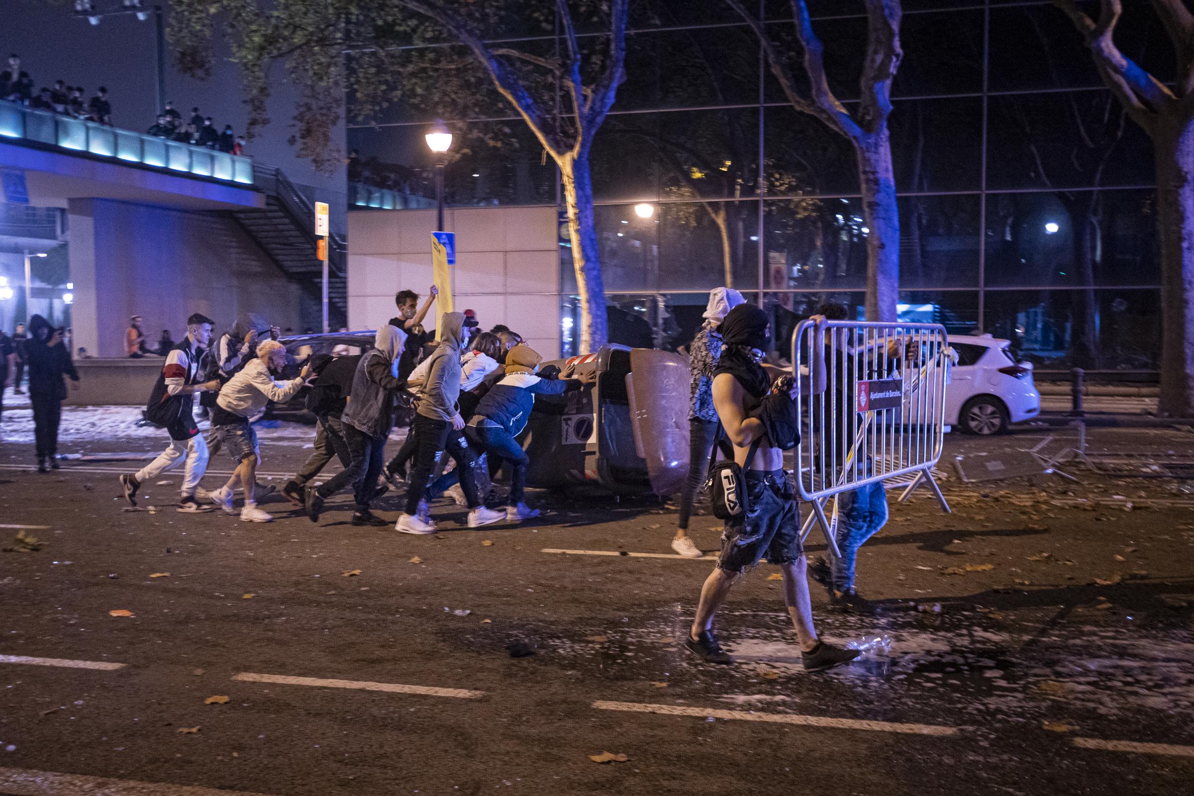 A group of young people move the containers and metallic fences to use them as barricades against...