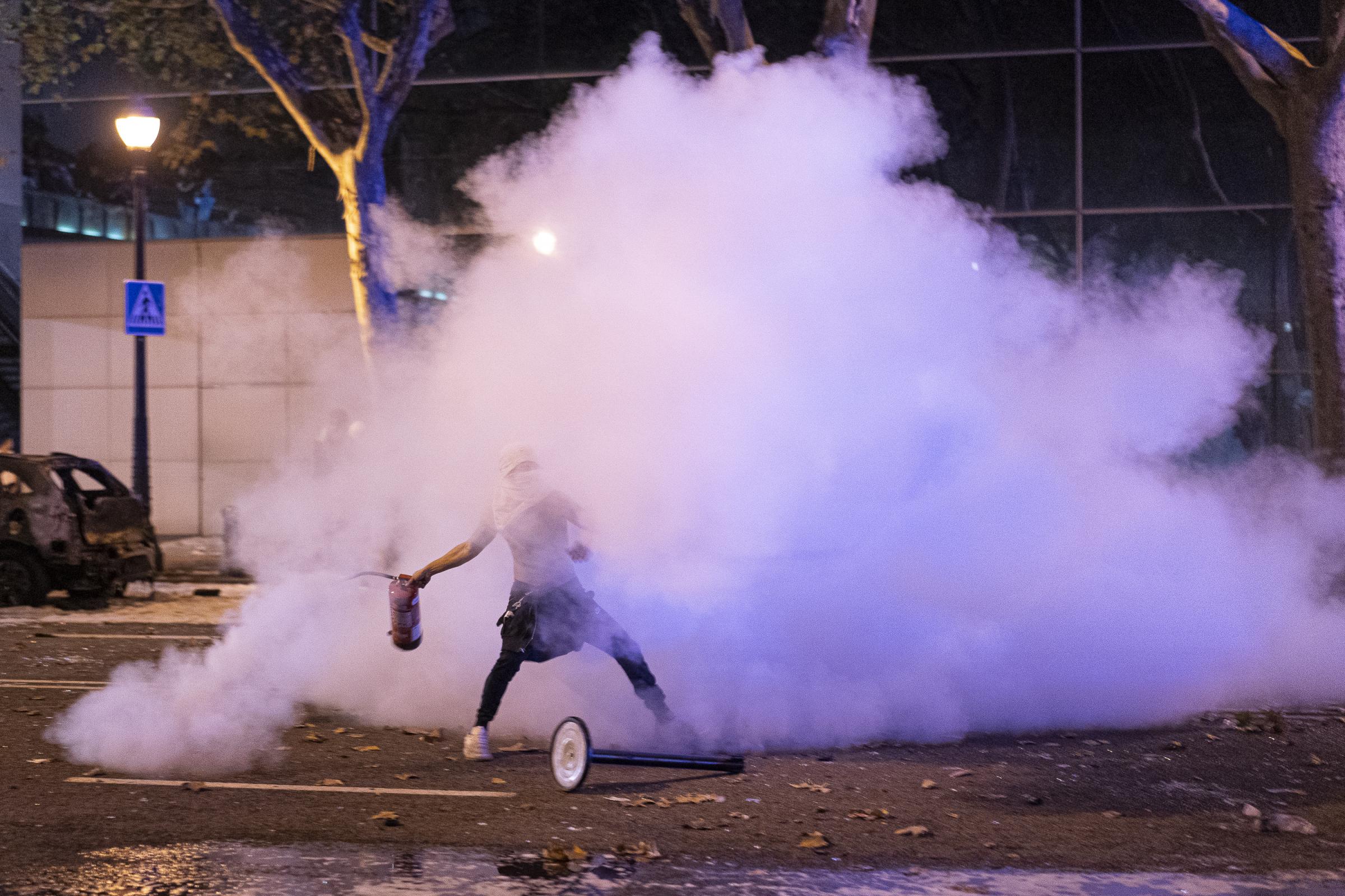 A young man throws a fire extinguisher after emptying it towards the police line. Friday night...