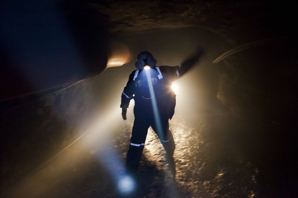 A miner guides a truck inside a gold mine.