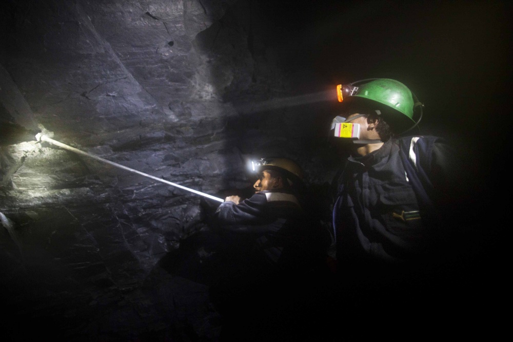 Two miners drill inside a goldmine