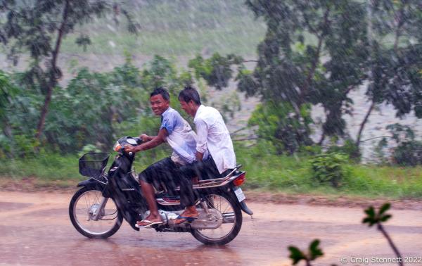 BANTEAY CHHMAR. CAMBODIA-MAY 25: Two young men ride on a motorcycle passing the Khmer Monastic Temple Complex of Banteay Chhmar,Banteay Meanchey, Cambodia on May 25, 2012.. The rainy season in Cambodia brings huge problems for the temple of Banteay Chhmar as the rain has over time undermined the temples Bas Relief-foundations. Banteay Chhmar, meaning 'The Citadel of the Cats' was built by Khmer King Jayavarman 7th (1181-1219) in the 12th Century. According to the UNESCO world heritage centre the temple is a unique complex of the Angkorian period of structural style. However, the temple complex due to its geographical isolation coupled with the effects of time and the elements is slowly crumbling and being reclaimed by the surrounding jungle. Teams of stone masons and archeologists with assistance from the Global Heritage Fund and Cambodian government are mounting a rescue mission in order to stem the temple's continued collapse and reclamation by the surrounding jungle.(Photo by Craig Stennett/Getty Images)