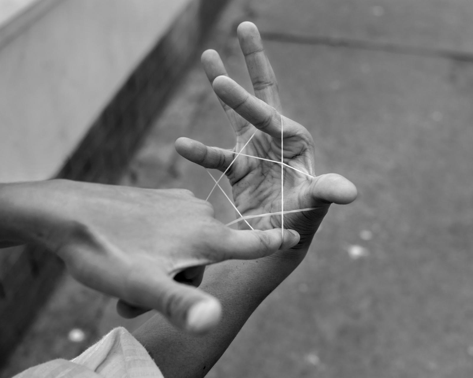A child makes a star with a elastic band in Hossaini Dalan.