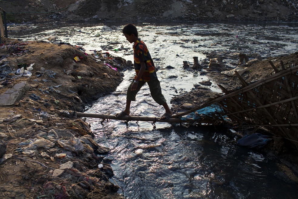 A boy crosses over a puddle of ...nd leather waste at Hazaribagh.
